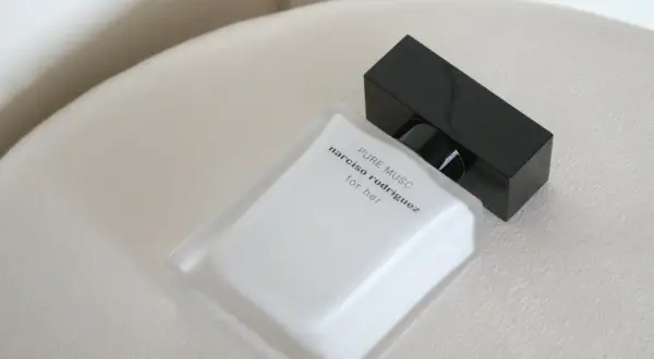Elegancka butelka perfum Narciso Rodriguez Pure Musc for her, z czarną nakrętką, na jasnym tle.
