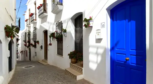 Calle empedrada con casas blancas y puertas azules vibrantes. Un lugar perfecto para descubrir qué hacer en Mojácar.