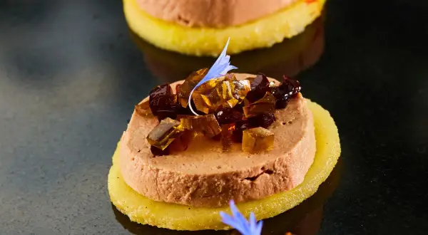 Délicieuse terrine de foie gras sur une tranche d'ananas, garnie de dés de gelée et d'une fleur bleue. Un vrai régal pour savoir comment démouler une terrine de foie gras.