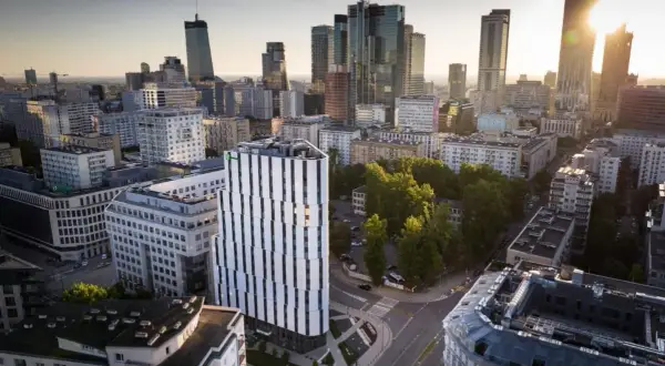 Widok na miasto z nowoczesnym budynkiem Holiday Inn Twarda w centrum. W tle wieżowce i zieleń.