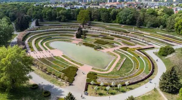 Widok z lotu ptaka na park Cytadela z jeziorem, tarasami i alejkami. W tle zabudowania miejskie.