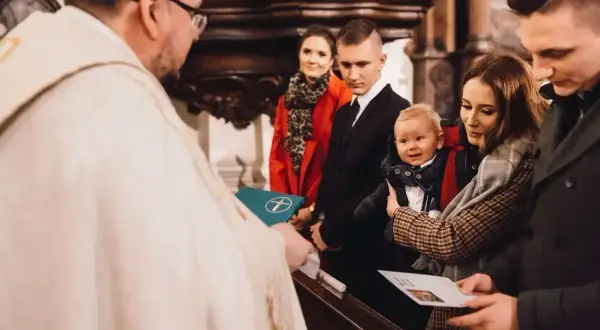Rodzina świętuje, kiedy chrzci się dzieci. Ksiądz błogosławi niemowlę trzymane przez matkę, podczas gdy ojciec i chrzestni patrzą z dumą.
