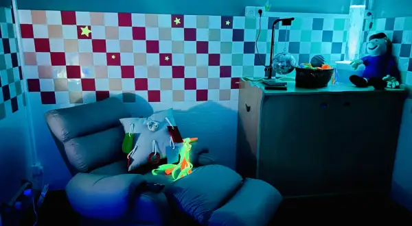 Chaise confortable et lumineuse pour une séance snoezelen, avec des étoiles au mur et une colonne à bulles.