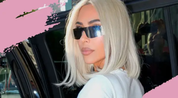 Frau mit platinblonden Haaren und futuristischen Sonnenbrillen steigt aus einem Auto.