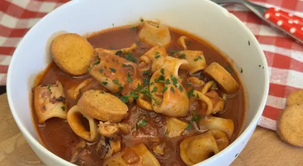 Un invitante piatto di moscardini in umido, ricchi di sapore e guarniti con prezzemolo fresco, accompagnati da crostini dorati.