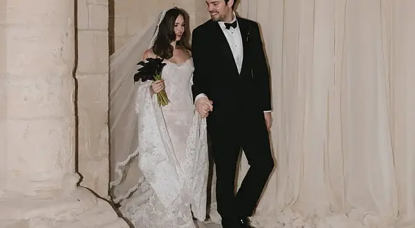 Novia con velo y ramo de **stella banderas** negras, y novio de traje, saliendo de una iglesia.