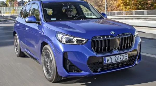 Niebieskie x1 bmw z kierowcą w okularach przeciwsłonecznych jedzie po drodze.