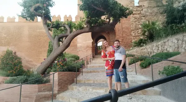 Pareja posando en escalinatas de piedra con un árbol retorcido y murallas de cañarete Almería de fondo.
