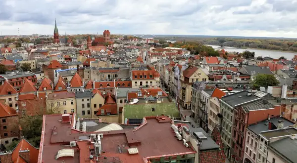 Widok na **Toruń stare miasto** z lotu ptaka. Czerwone dachy kamienic, kościelne wieże i Wisła w tle.