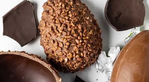 Uova di Pasqua al cioccolato, una con nocciole, altre rotte. Un assaggio delle loro origine.