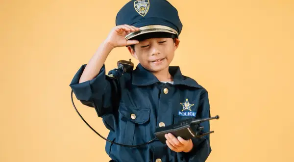 Dziecko w stroju policjantki, z czapką i krótkofalówką, gotowe do akcji.
