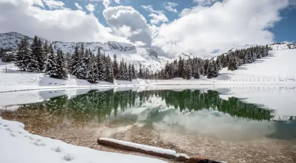 Lac d'altitude enneigé, reflétant les sapins et les montagnes. Idéal pour découvrir que faire autour de Villard de Lans en hiver.