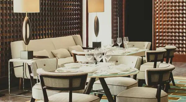 Eleganza in un ristorante di Milano: tavoli apparecchiati, divani accoglienti e luci soffuse creano un'atmosfera raffinata.