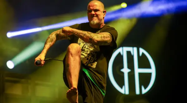Phil Anselmo z Pantery w Polsce, z mikrofonem w dłoni, na tle sceny z oświetleniem.