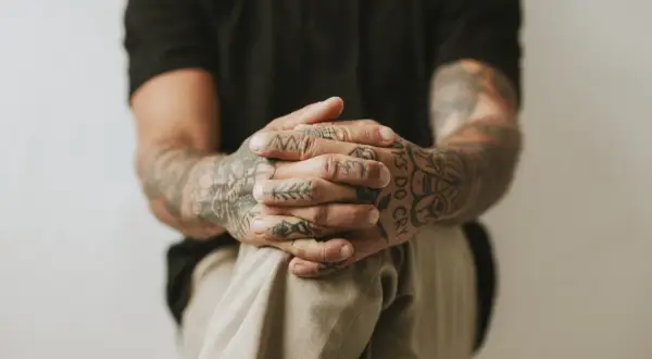 Dłonie z tatuażami wykonanymi metodą handpoke, z widocznym napisem "BOYS DO CRY".