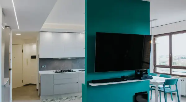 Un moderno cartongesso open space divide cucina e zona living con TV. Luce soffusa e colori vivaci.