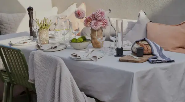 En vacker dukning utomhus med blommor, ljus och nybakat bröd. En inbjudande scen för en somrig middag.