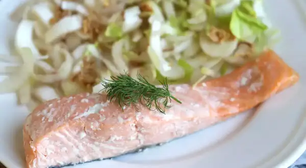 Un délicieux pavé de saumon rose, garni d'aneth frais, servi avec une salade croquante de fenouil et d'oignons.