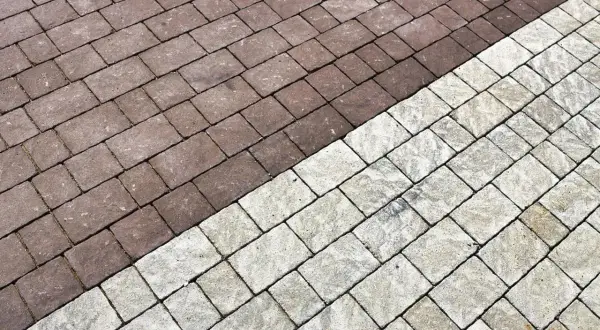 Pavimentazione esterna con blocchi di cemento color tortora e grigio chiaro, disposti a spina di pesce.