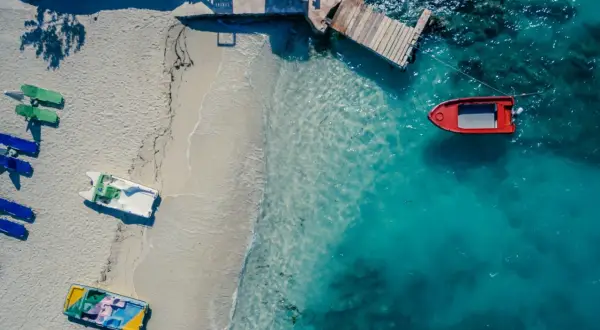 Widok z lotu ptaka na plażę z łodziami i turkusową wodą. Golem Albania atrakcje to idealne miejsce na wakacje.