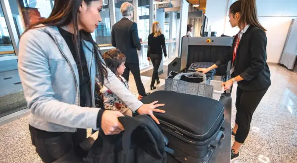 Familj vid säkerhetskontrollen på flygplatsen, redo för resan med sitt mått handbagage flyg.