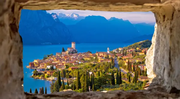 Vista incantevole del castello di Malcesine affacciato sul lago, con montagne sullo sfondo.