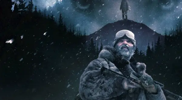 Film na podstawie książki Mroza. Mężczyzna w futrzanej kurtce i goglach z karabinem na tle ośnieżonego lasu i wzgórza, na którym stoi samotna postać.