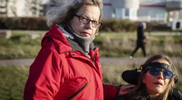 Catrin Hedlund Seyhan med handen på en kvinna i rullstol utomhus.