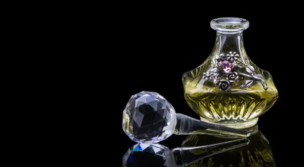 Elegancka buteleczka perfum z ozdobnym motywem kwiatowym i kryształowym korkiem. Zapach piżma unosi się, kusząc zmysły.