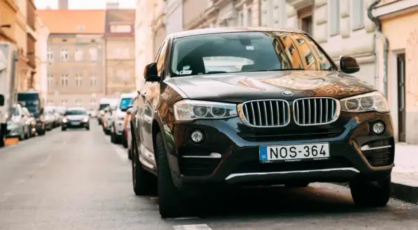 Czarny SUV zaparkowany na ulicy, przypominający o przepisach dotyczących zastawiania bramy wjazdowej.