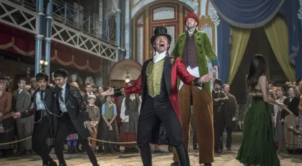 Król rozrywki, P.T. Barnum, w cyrkowym stroju wita publiczność. W tle widzimy jego artystów i widzów.