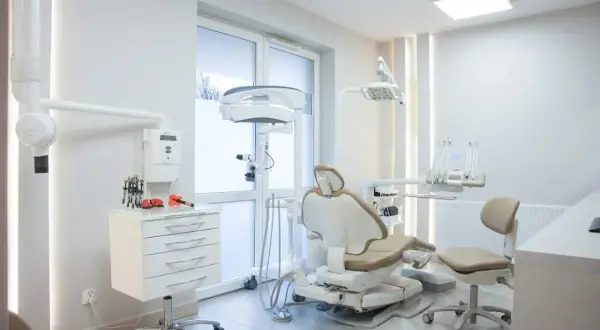 Nowoczesny gabinet stomatologiczny z fotelem dentystycznym i sprzętem medycznym.