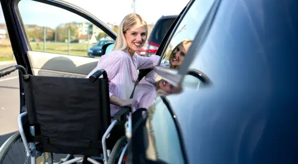Donna sorridente accanto a una carrozzina, pronta per un viaggio in auto. Il rigo e3 730 è un'ottima soluzione per la mobilità.