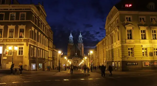 Wieczorne Gniezno: oświetlona ulica prowadzi do katedry, a budynki po bokach tworzą malowniczy widok. Atrakcje miasta nocą zachwycają.