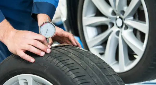 Un meccanico misura il battistrada di uno pneumatico 4 stagioni per capire quanti km fanno ancora.