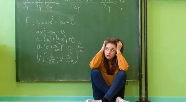 Dziewczyna zmagająca się z zadaniami matematycznymi na tablicy, symbolizująca dyskalkulię u dorosłych.
