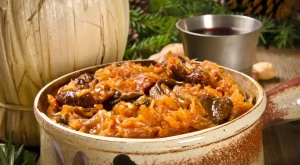 Aromatyczny bigos z różnymi rodzajami mięsa, serwowany w glinianym naczyniu, idealny na zimowe wieczory.