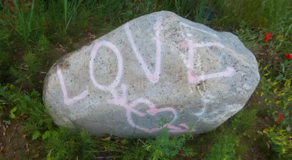 Duży kamień z różowym napisem LOVE i sercem.