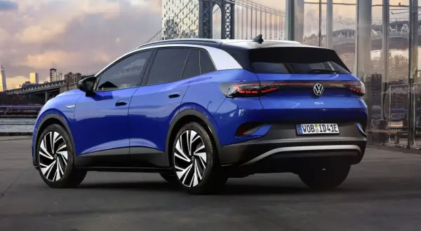 Niebieski Volkswagen ID.4 z imponującym zasięgiem, zaparkowany na tle miejskiej panoramy z mostem.