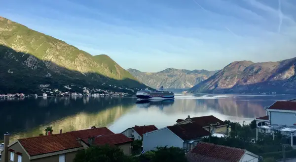 Widok na zatokę w Czarnogórze z górami w tle i statkiem wycieczkowym. Czy Czarnogóra jest bezpieczna? Tak, to spokojne miejsce na wakacje.