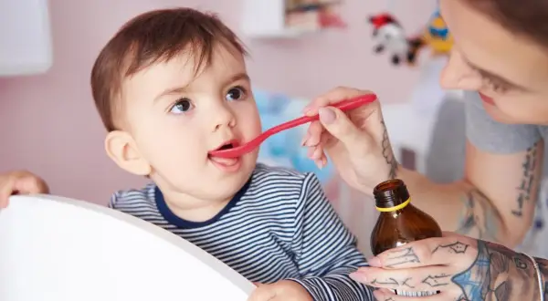 Mama podaje dziecku witaminę D na łyżeczce. Ważne jest, ile witaminy D dla 2 latka, by zapewnić mu zdrowy rozwój.