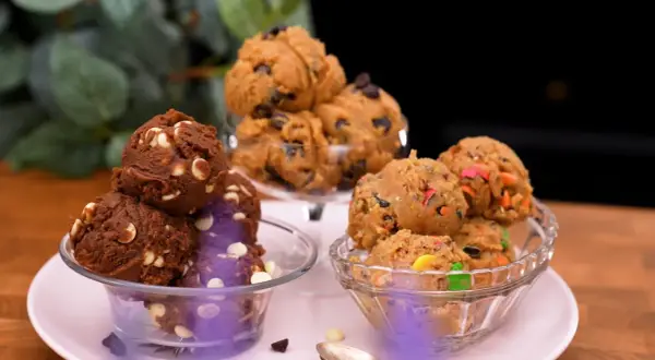 Tre skålar med olika sorters cookie dough recept: choklad med vita chokladknappar, klassisk med chokladknappar och en med färgglada godisbitar.