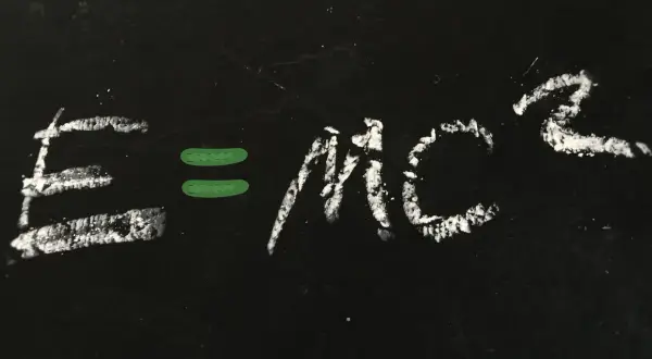 Równanie E=mc² napisane kredą na czarnej tablicy.
