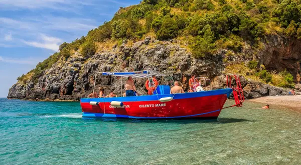 Gita in barca a Marina di Camerota, con gente che si gode il mare cristallino e la costa rocciosa. Perfetto per scoprire cosa fare a Marina di Camerota.