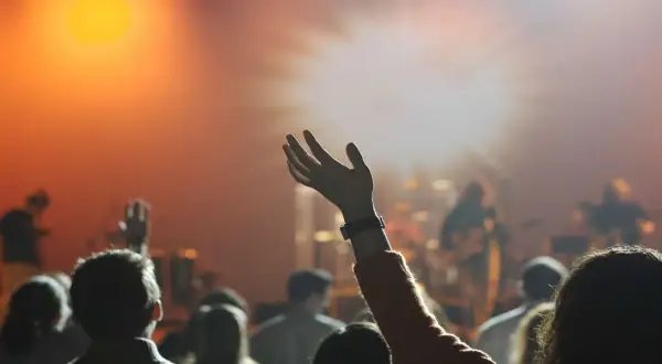 Menschen mit erhobenen Händen in einem Gottesdienst. Sie sind Teil der Pfingstbewegung, die sich durch lebendige Anbetung auszeichnet.