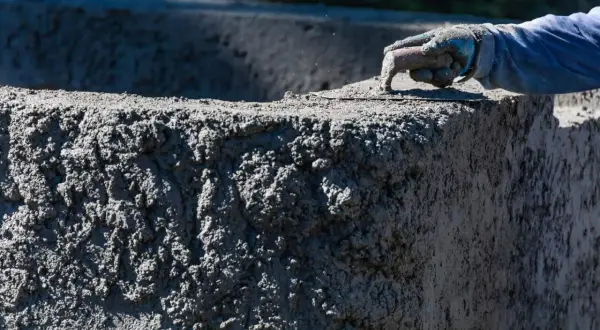 Ręka w rękawicy wygładza świeży beton B20. Sprawdzamy beton B20 cena za m3.
