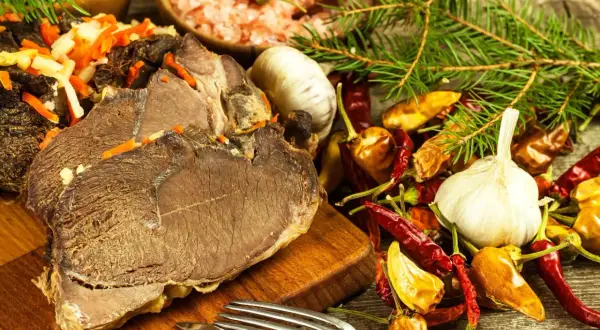Gotujesz dziczyznę? Na stole pieczone mięso, czosnek, papryczki chili i przyprawy. Idealne składniki, by dowiedzieć się, jak przyrządzić dziczyznę.