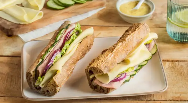 Deux sandwichs généreux, garni de jambon, fromage, concombre et oignon rouge. Le meilleur sandwich jambon fromage pour un déjeuner parfait.