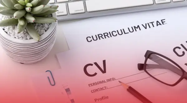Na biurku leżą dokumenty CV, okulary i ołówek. Roślina w doniczce i klawiatura dopełniają scenę.