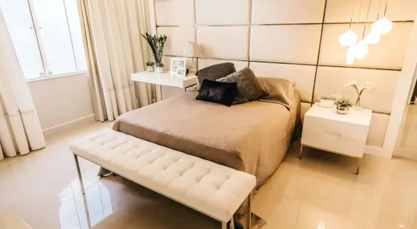Elegancka sypialnia z tapicerowanym zagłówkiem, który pokazuje, jak zamontować panele tapicerowane na ścianie. Jasne kolory i minimalistyczne meble tworzą przytulną atmosferę.